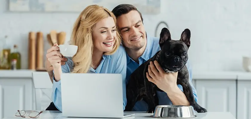 Uomo e donna bevono un caffè e abbracciano il loro cane sul tavolo della cucina – Come superare la fase di dentizione